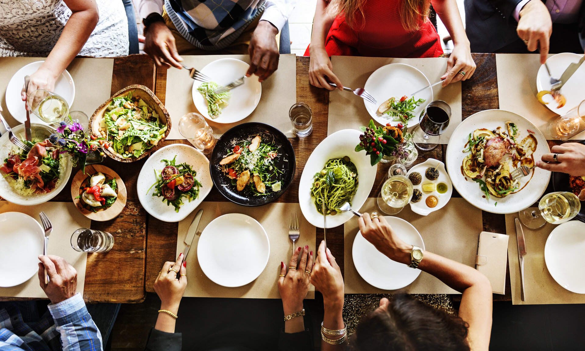 A group of people sitting around a table with plates of food and glasses of wine.