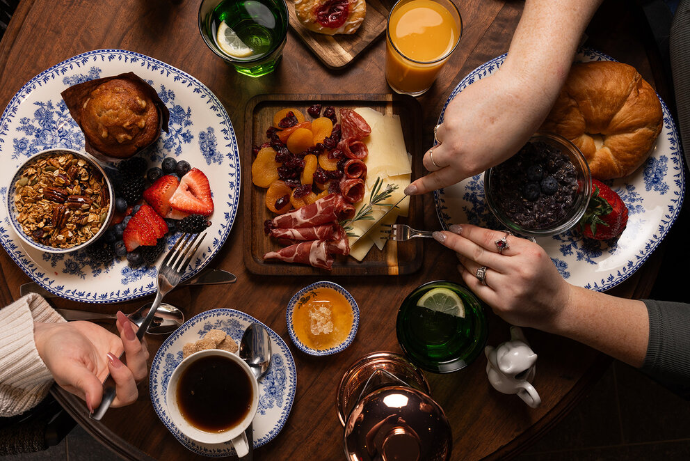 A breakfast table with a variety of foods including pastries, fresh fruit, and a charcuterie board.