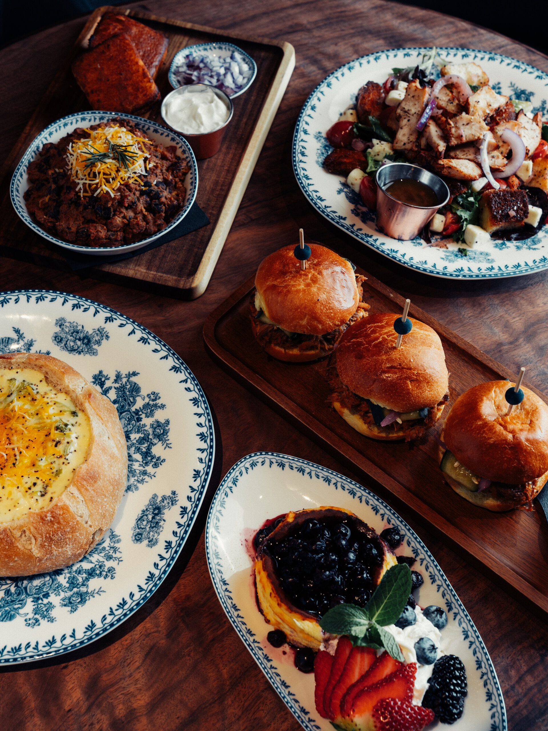 A table with various dishes, including burgers, salads, and desserts.